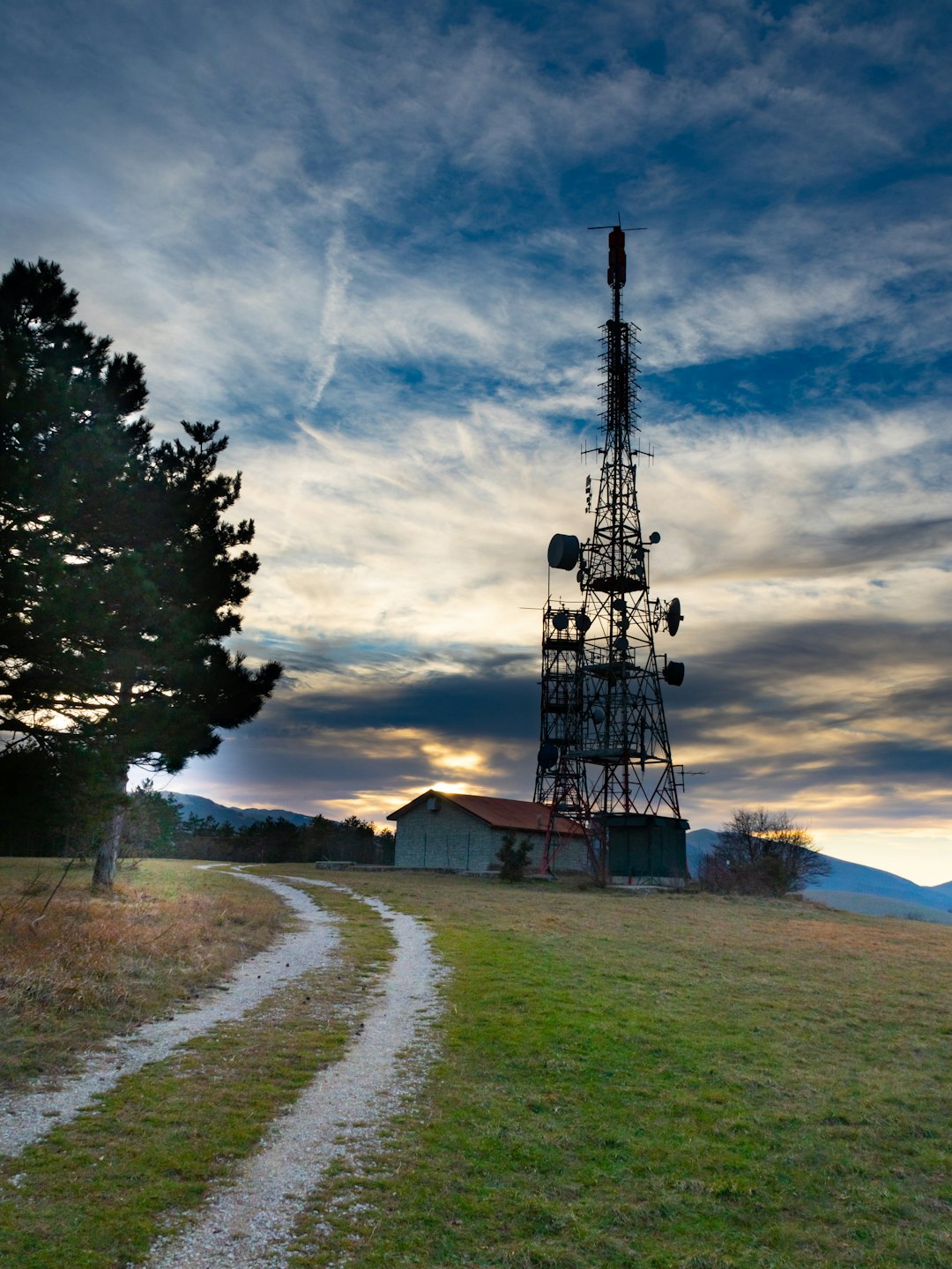 Communication tower and buildings sit on a grassy hilltop.
