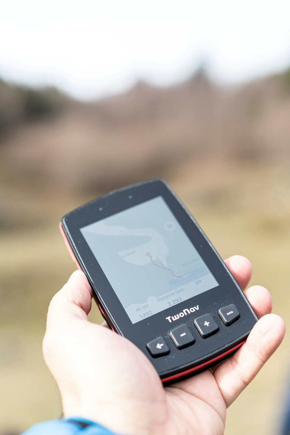 Hand holding GPS device displaying map and route information.