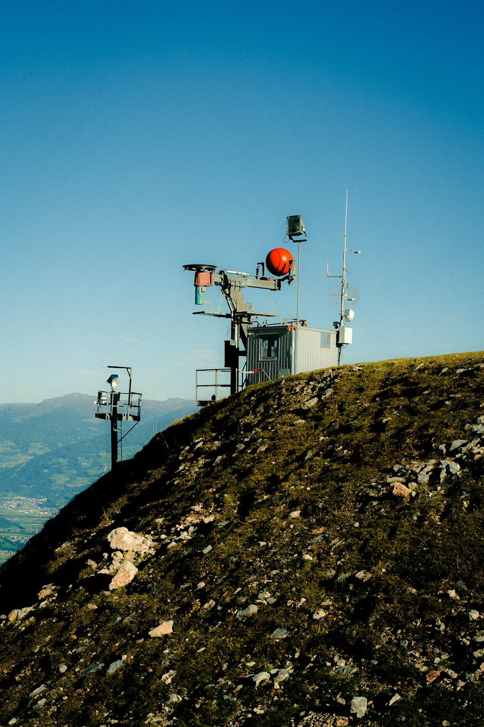 Remote weather station with a red dome sits on a mountain.